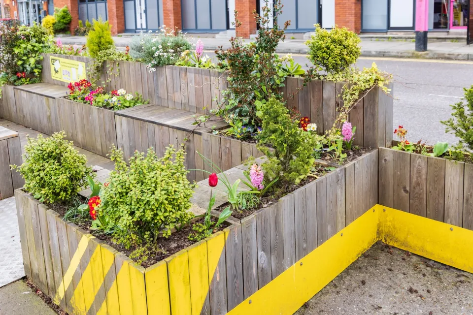 Parklet with wooden benches and flower boxes on street in Ireland.